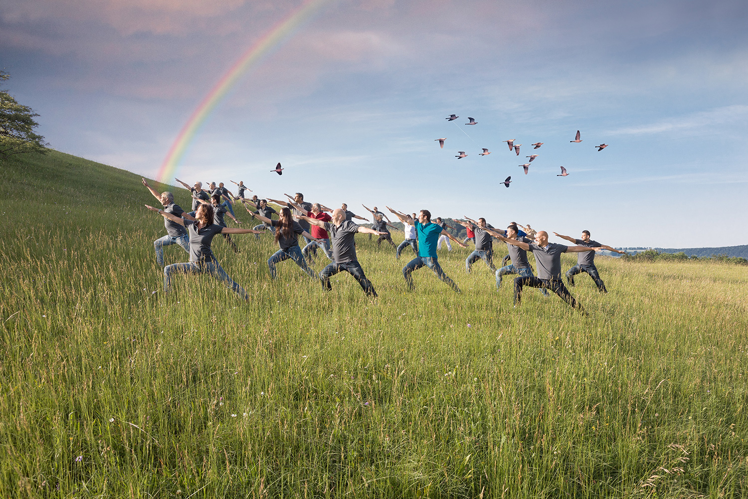 MBA team in meditative pose in nature with rainbow in the sky